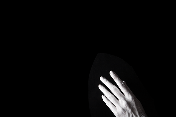 White painted hand in darkness disappearing off the bottom of the image