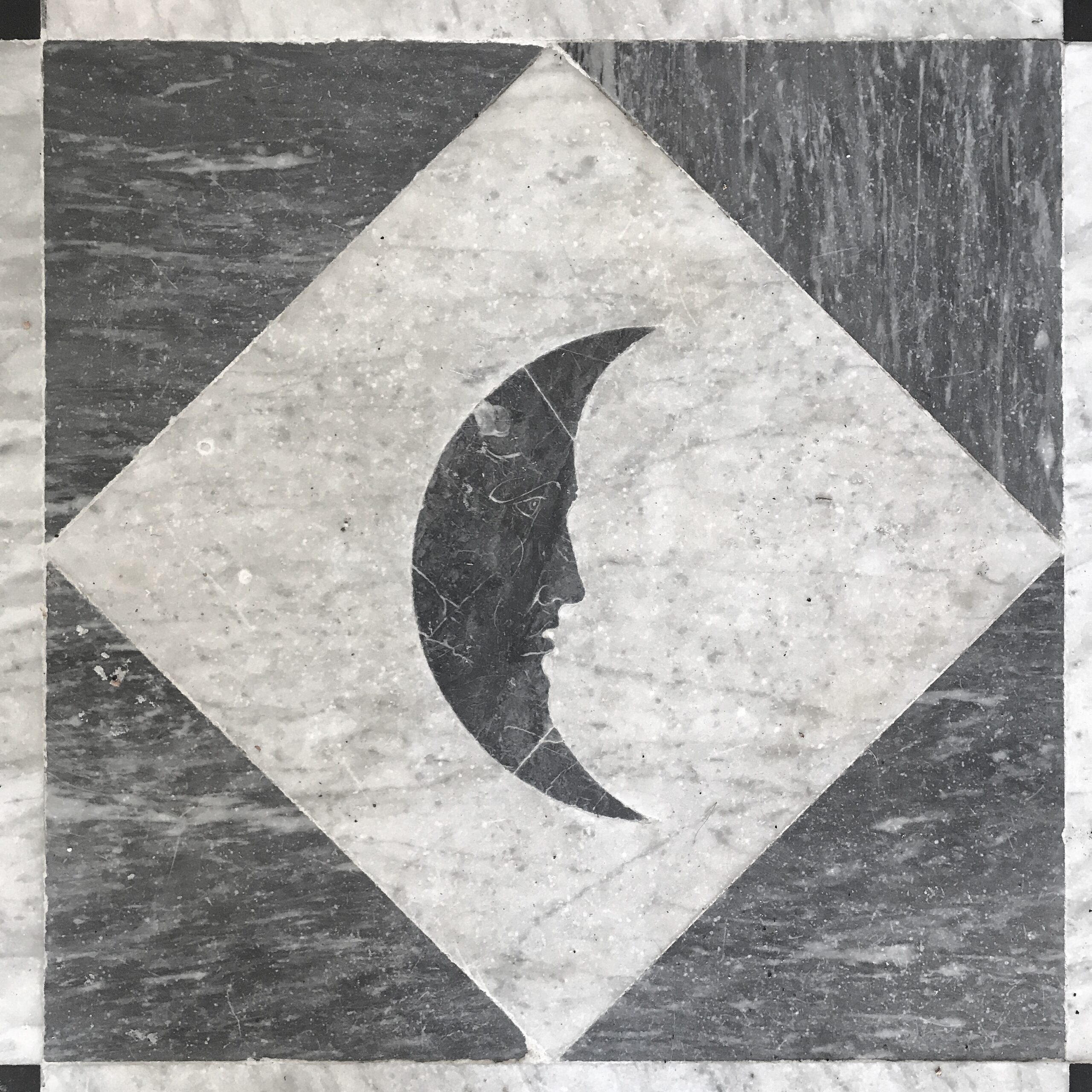 Black night: Dark grey crescent moon with a face, set against a pale grey diamond square